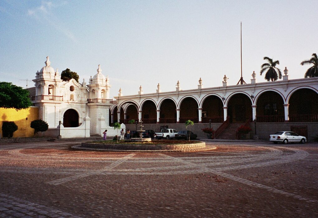 Casa Hacienda San José en Chincha: capilla blanca de dos torres y largo portal de arcos frente a una explanada