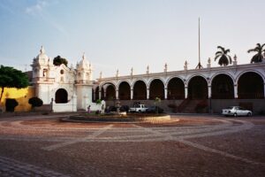 Casa Hacienda San José en Chincha: capilla blanca de dos torres y largo portal de arcos frente a una explanada