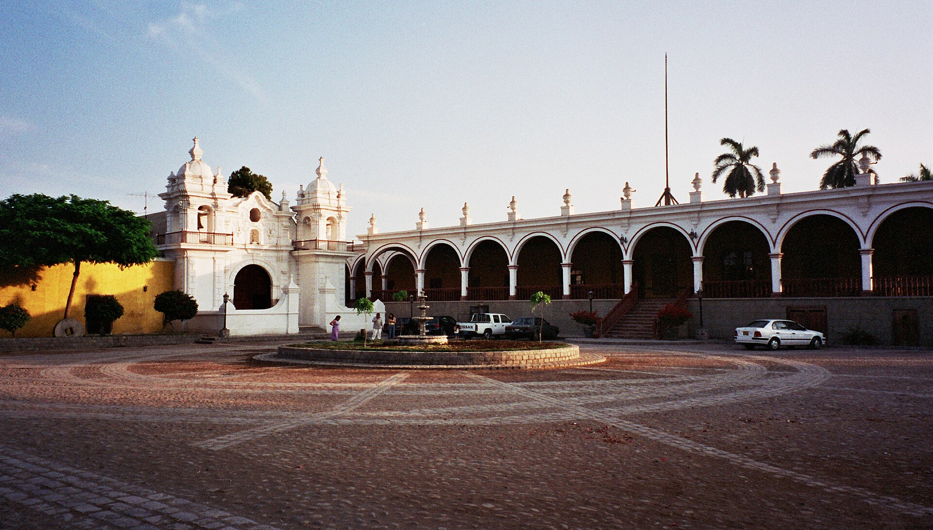 Casa Hacienda San José en Chincha: capilla blanca de dos torres y largo portal de arcos frente a una explanada