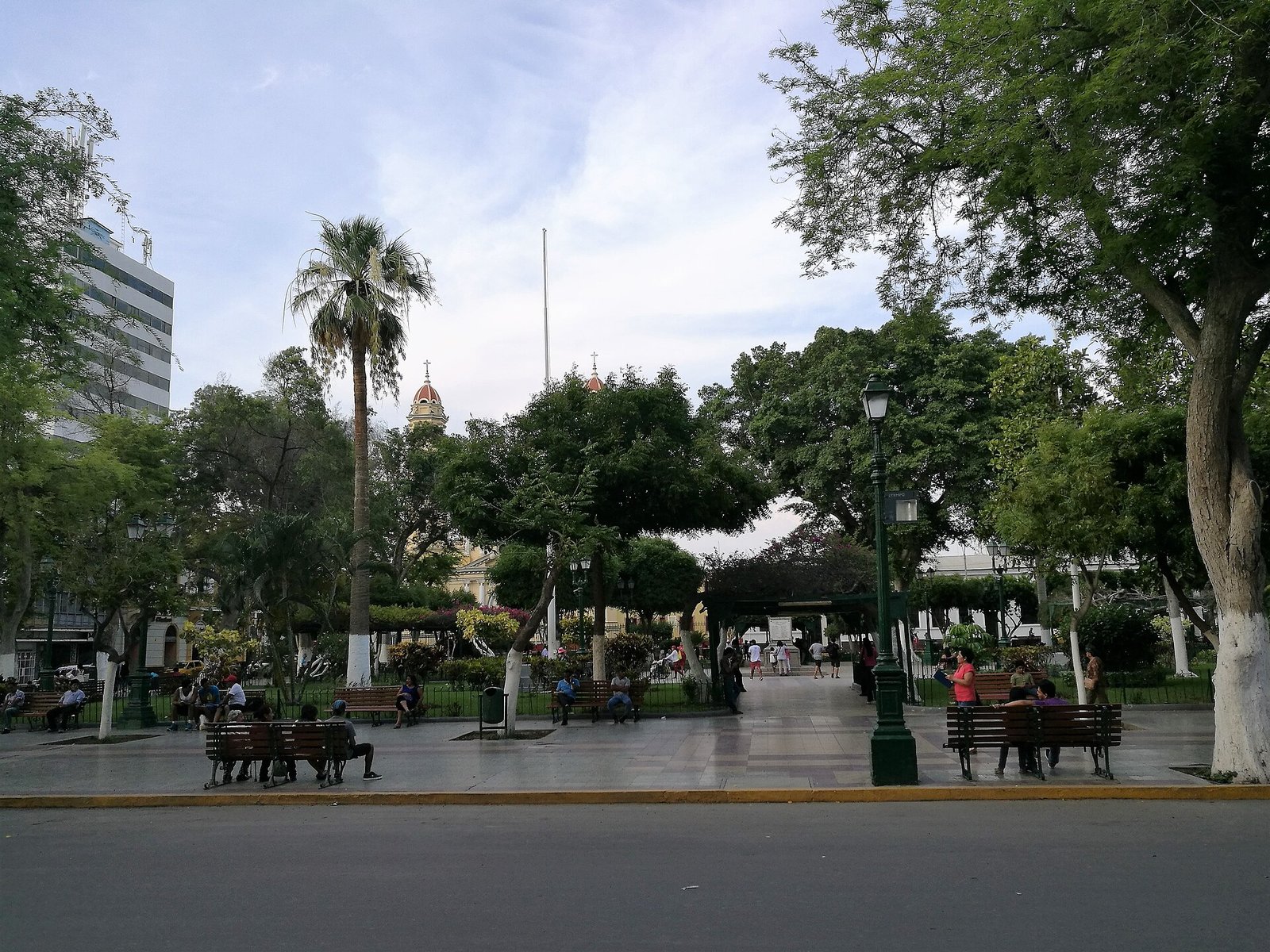 Plaza de Armas de Piura con árboles, bancas y la cúpula de la catedral al fondo